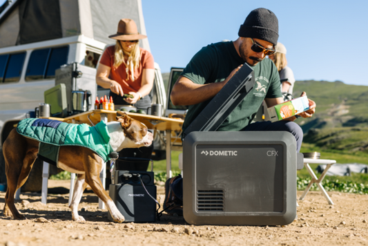 Man opening a Dometic CFX5 Cooler while camping with dog and wife