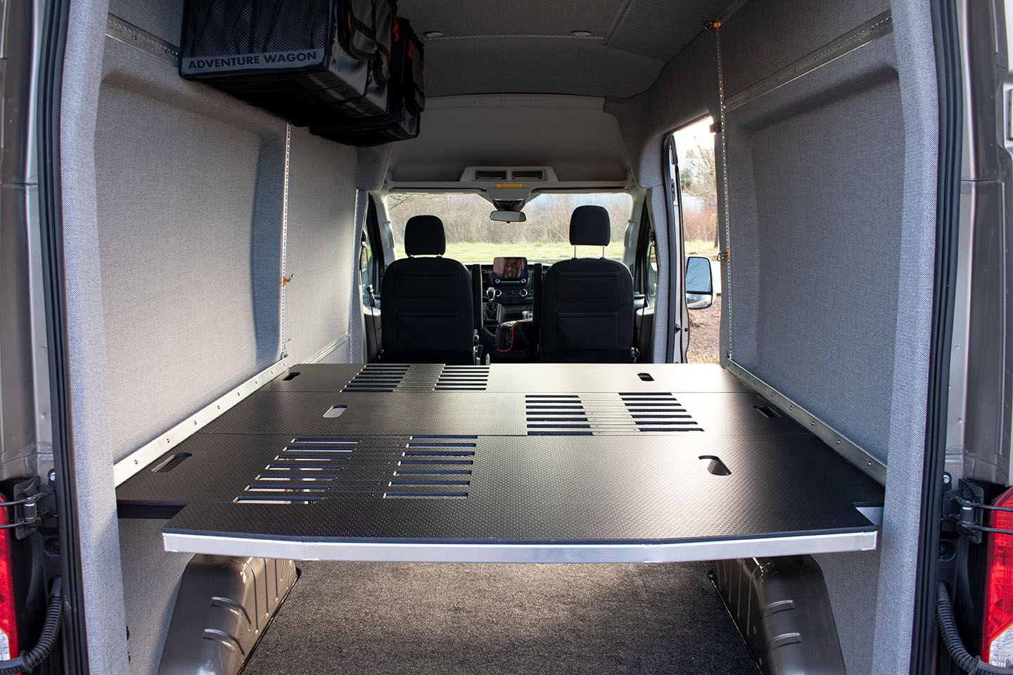 Adjustable van bed system shown in camper van shown from back