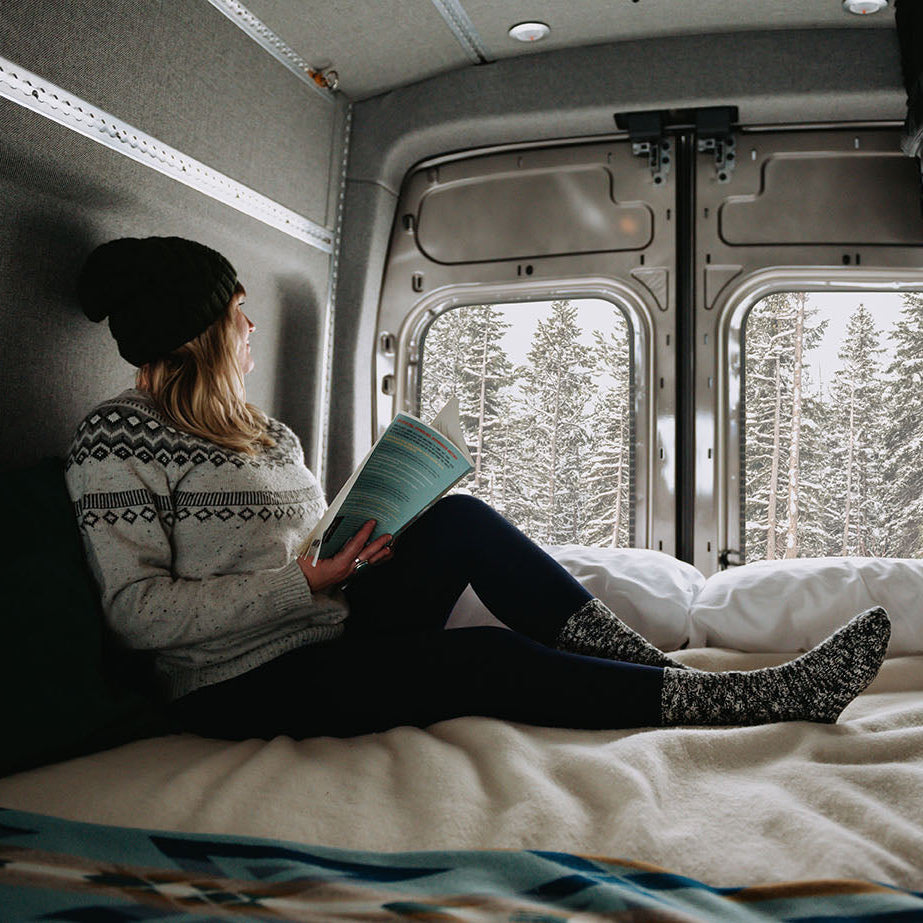 Woman lounging on adjustable van bed during winter