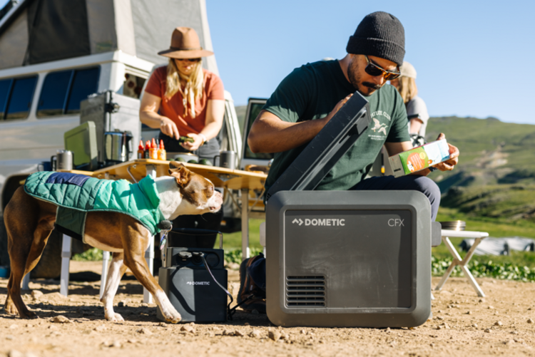 Man opening a Dometic CFX5 Cooler while camping with dog and wife
