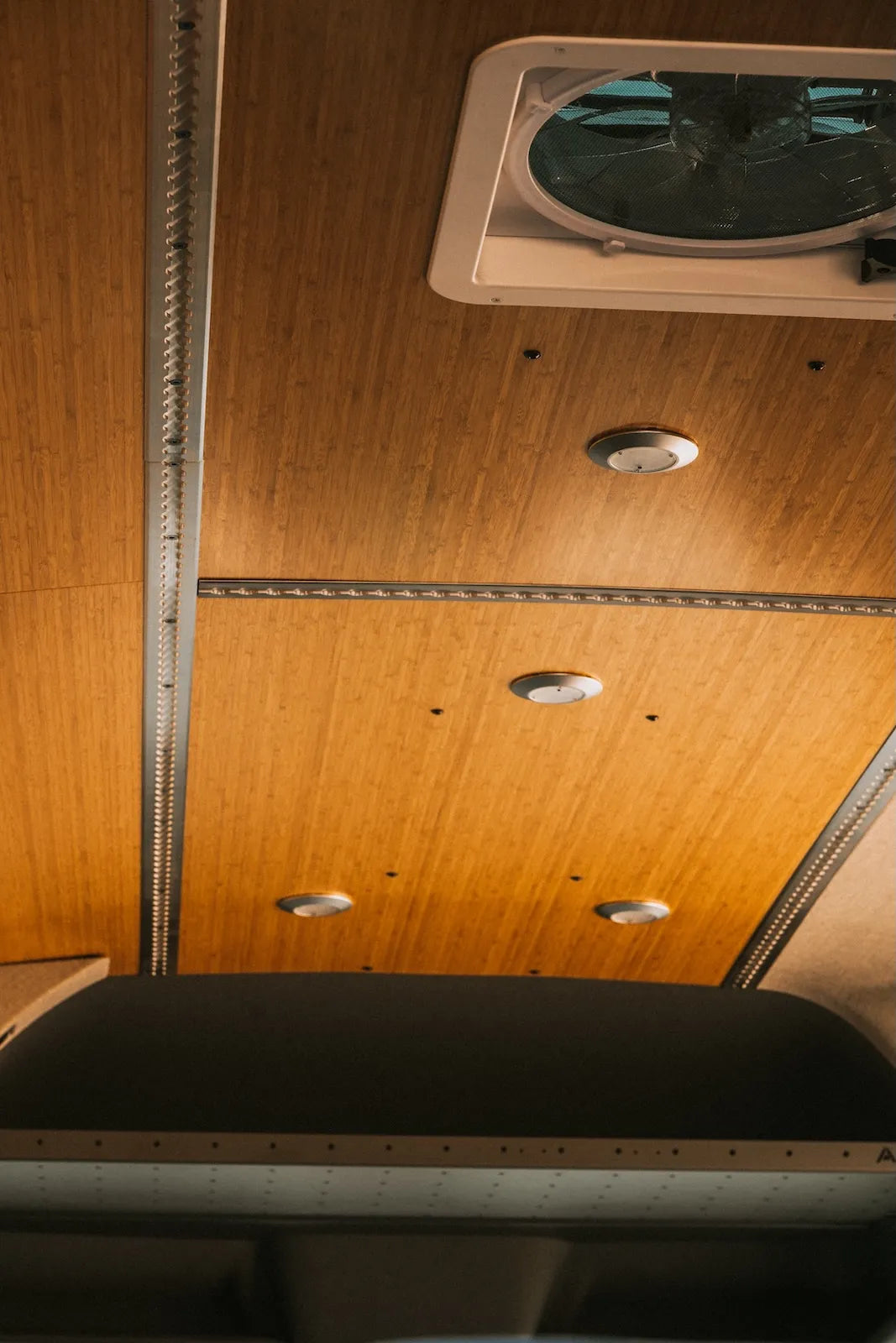 Adventure Wagon Factory Install camper van interior with bamboo ceiling panels, integrated lighting and a roof ventilation fan.