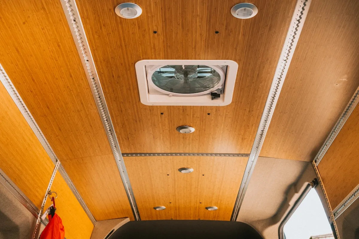 Adventure Wagon camper van bamboo ceiling with integrated recessed lights, roof vent fan and L-Track running through the finished interior.