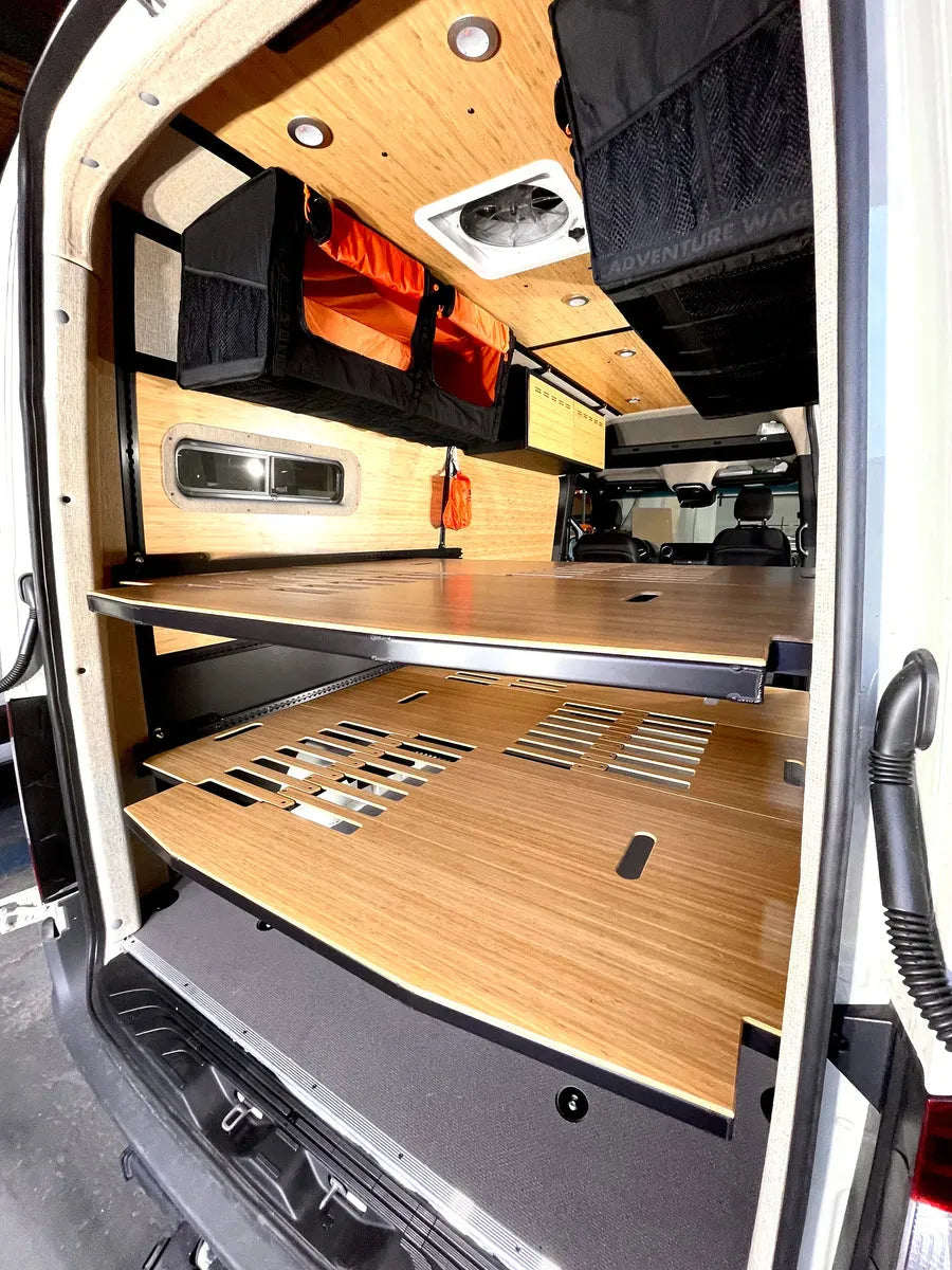 Adventure Wagon camper van interior showing modular two-level bed platform system with bamboo panels and overhead Mule Bags.