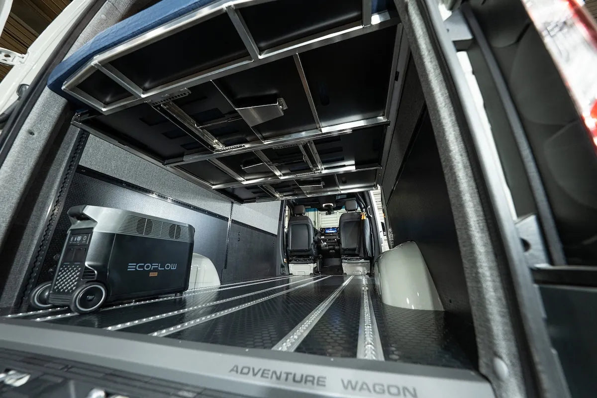 Rear Adventure Wagon camper van interior with an elevated modular bed platform creating open storage and usable cargo space underneath.