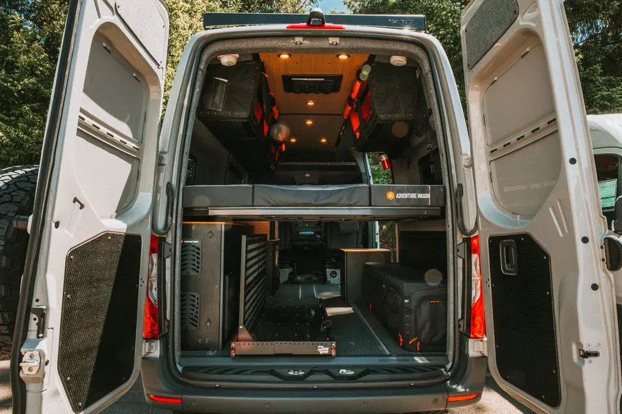 Adventure Wagon camper van interior storage setup with gear organized around a modular bed platform and L-track mounting system.