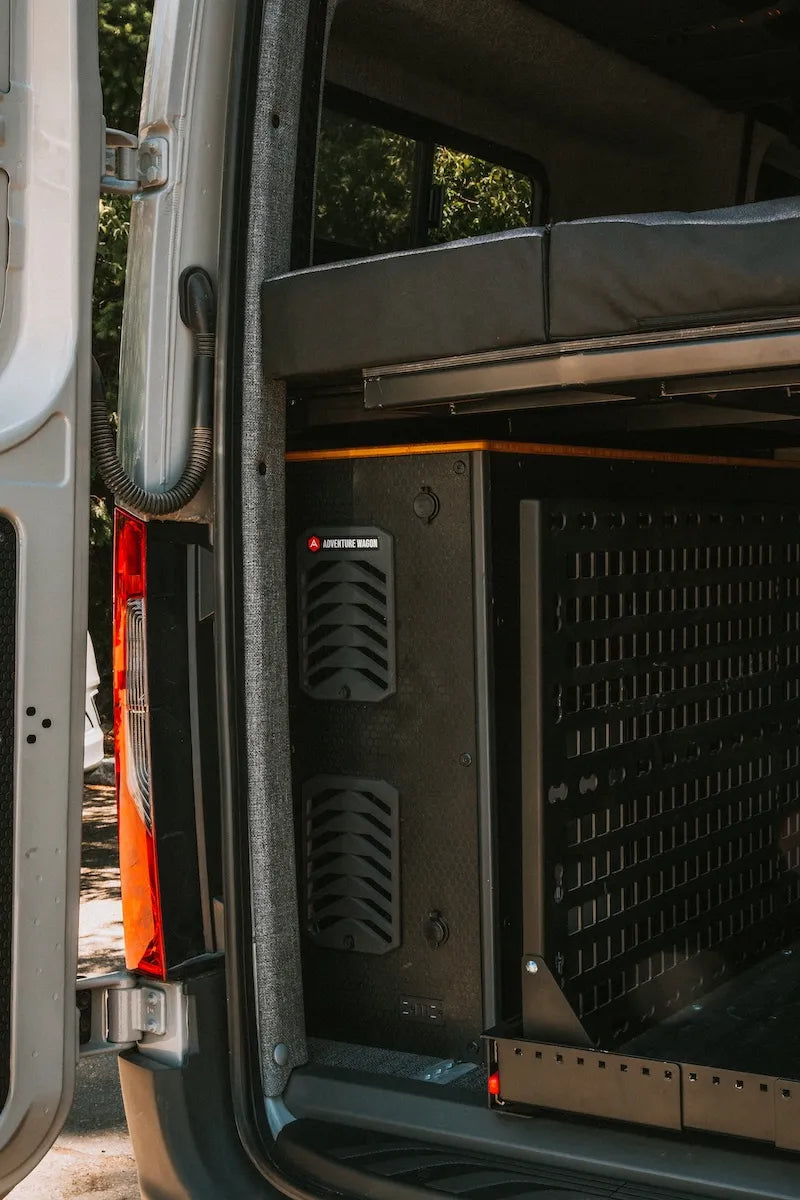 Adventure Wagon camper van interior with modular bed system, MOLLE-style wall storage and electrical system.