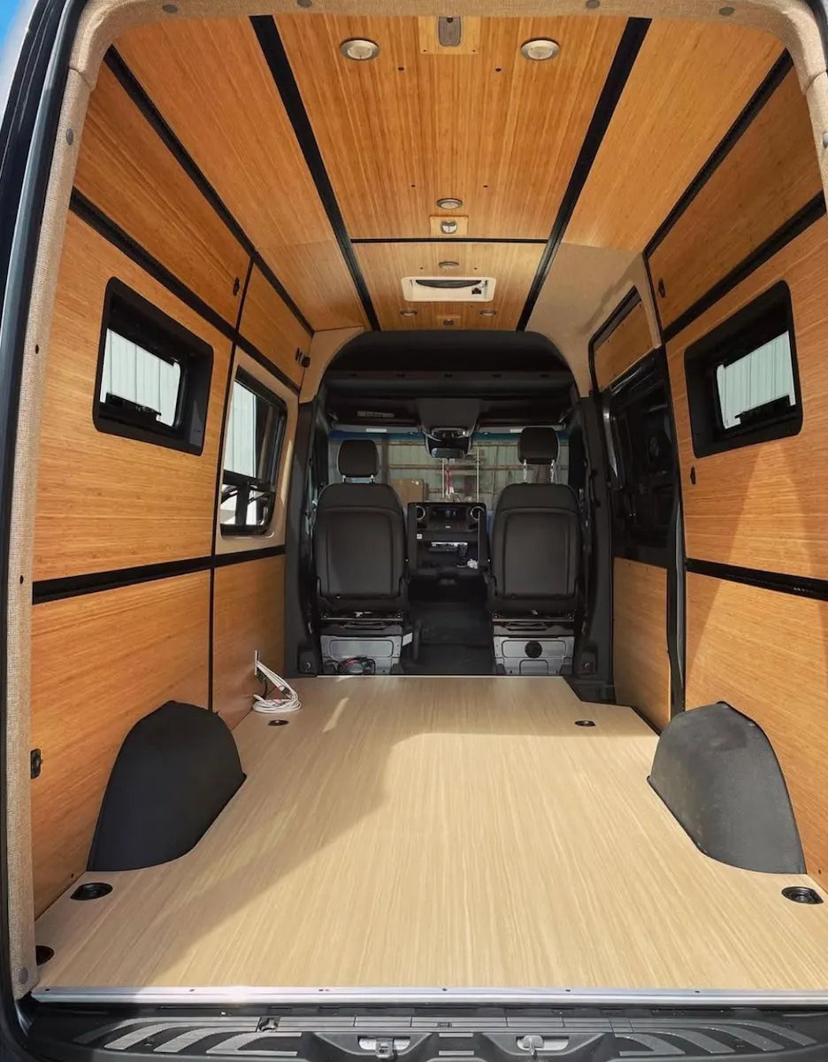 Empty Adventure Wagon camper van interior with bamboo ceiling and wall panels, integrated L-Track, windows and an open modular floor plan.