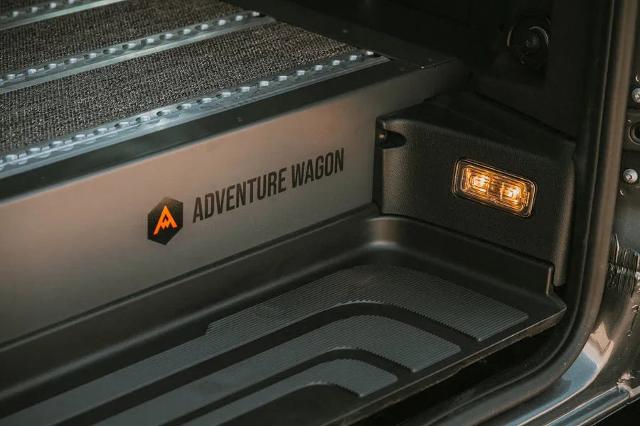 Close-up of Adventure Wagon branded camper van entry step and interior floor detail.