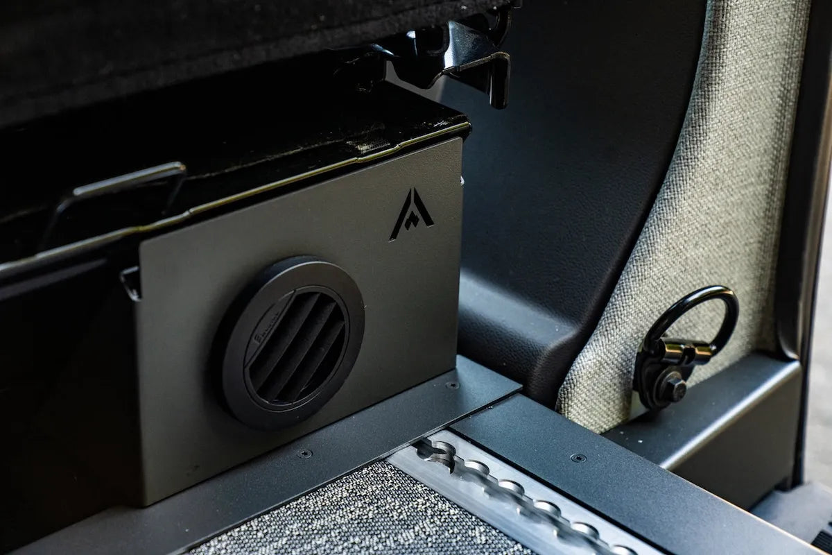 Close-up of an Adventure Wagon camper van Espar heater vent mounted beside the interior L-track floor and tie-down ring.