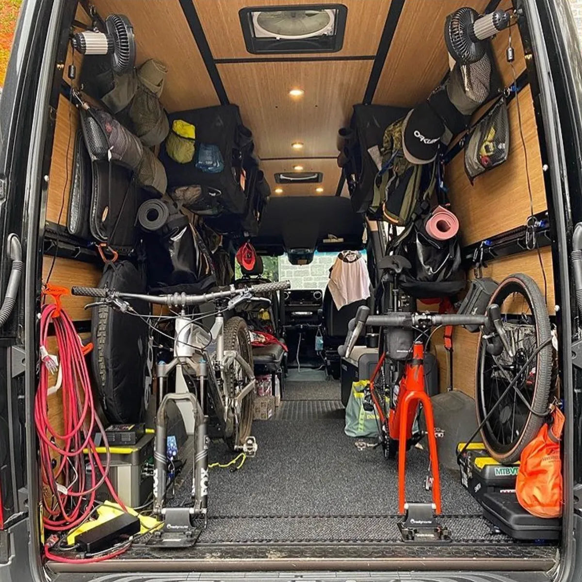 Rear of an Adventure Wagon camper van loaded with outdoor gear, storage bags, equipment and modular interior accessories for adventure travel.