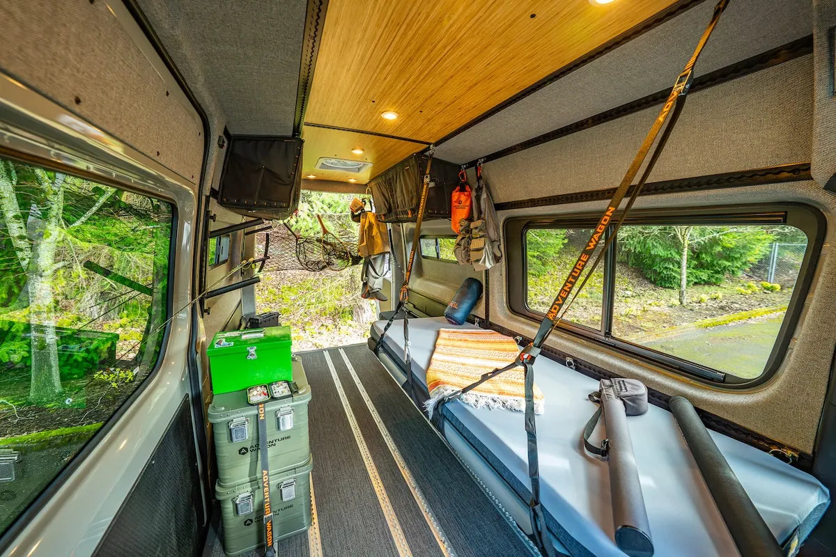 Adventure Wagon camper van interior configured with a modular raised Soogan Bunk bed, open floor space, gear storage, and removable equipment.
