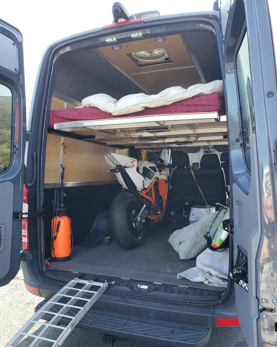 Adventure Wagon camper van interior with elevated bed platform and flexible open storage space underneath for bikes and outdoor gear.