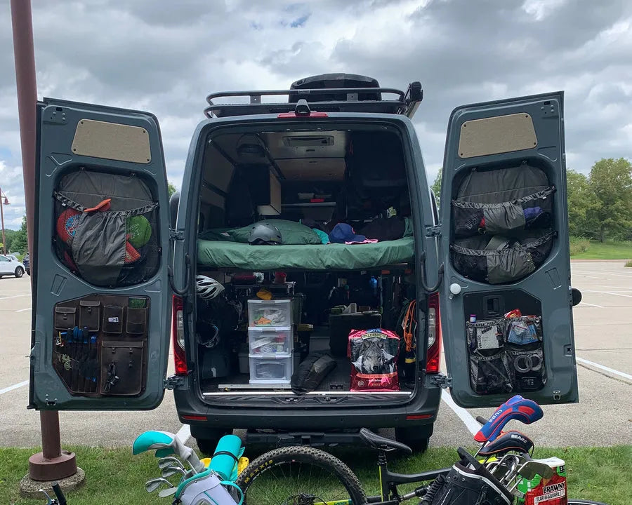 Adventure Wagon camper van interior customized for outdoor gear storage with modular wall panels, overhead storage and open cargo space.