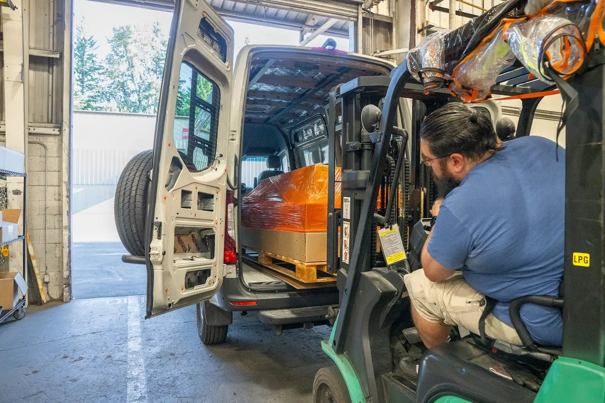 Adventure Wagon factory team unloading packaged camper van Interior System components from a Sprinter van using a forklift.