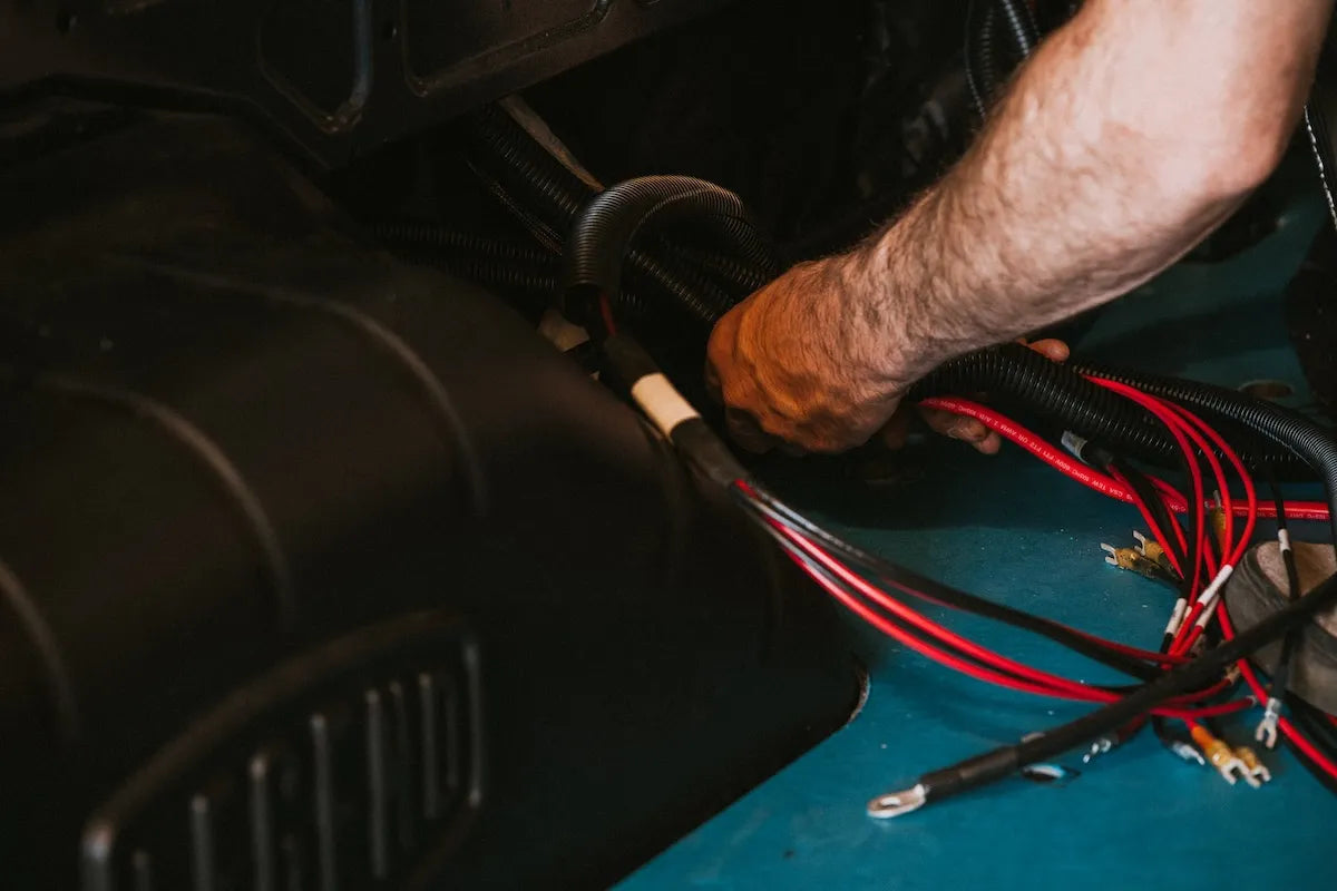Adventure Wagon Factory Install technician connecting electrical wiring inside a camper van during installation of the interior power system.
