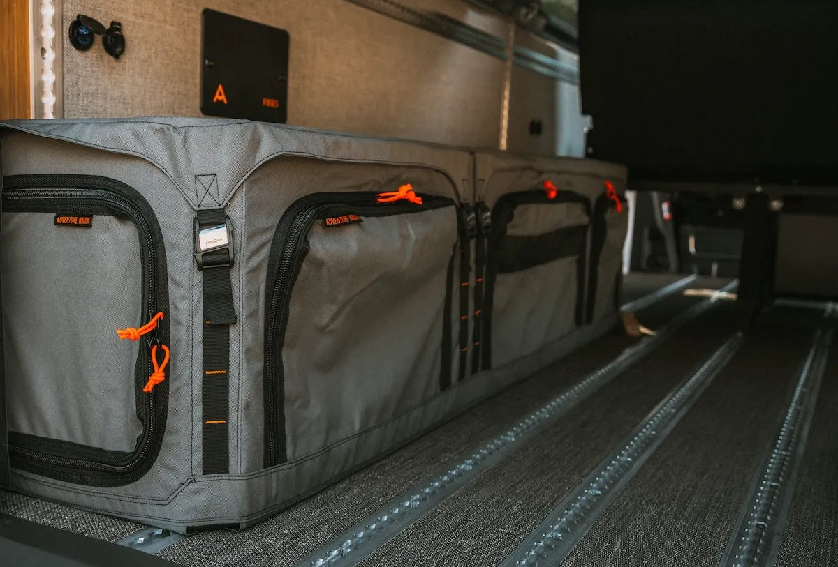 Adventure Wagon GOAT Locker installed at the rear of a camper van beside floor L-Track for organized wheel-well storage and secure gear mounting.