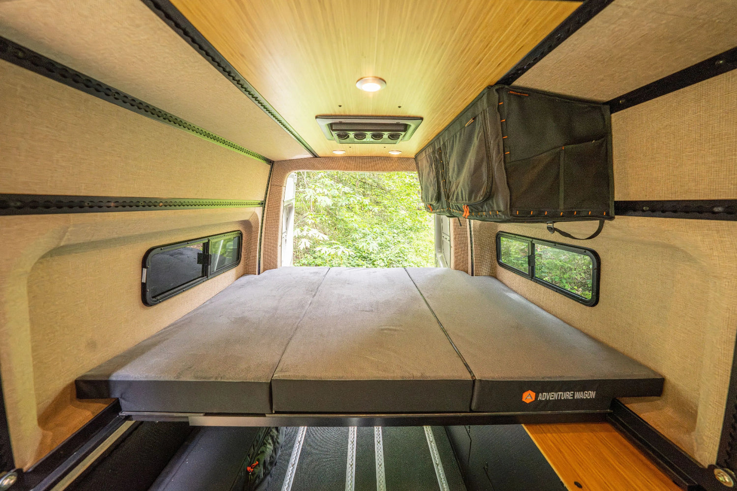 Adventure Wagon Guided Build 538 rear bed platform positioned between side windows inside the Mercedes Sprinter camper van.