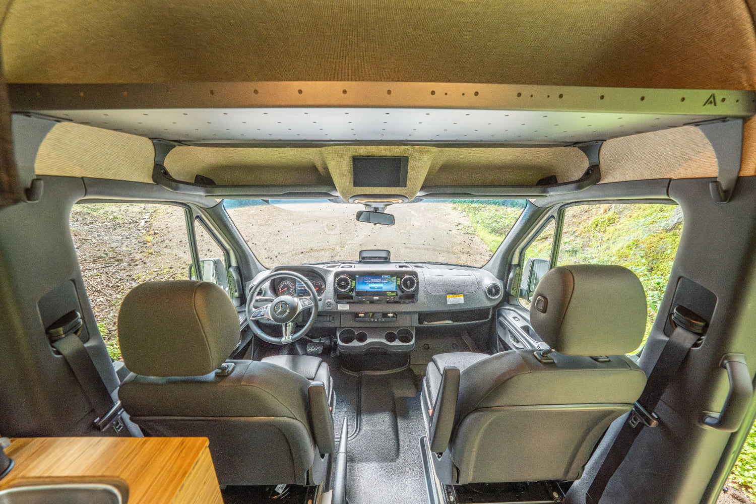 Adventure Wagon Guided Build 538 front cab interior with driver and passenger seats, overhead shelf, and integrated camper van storage.
