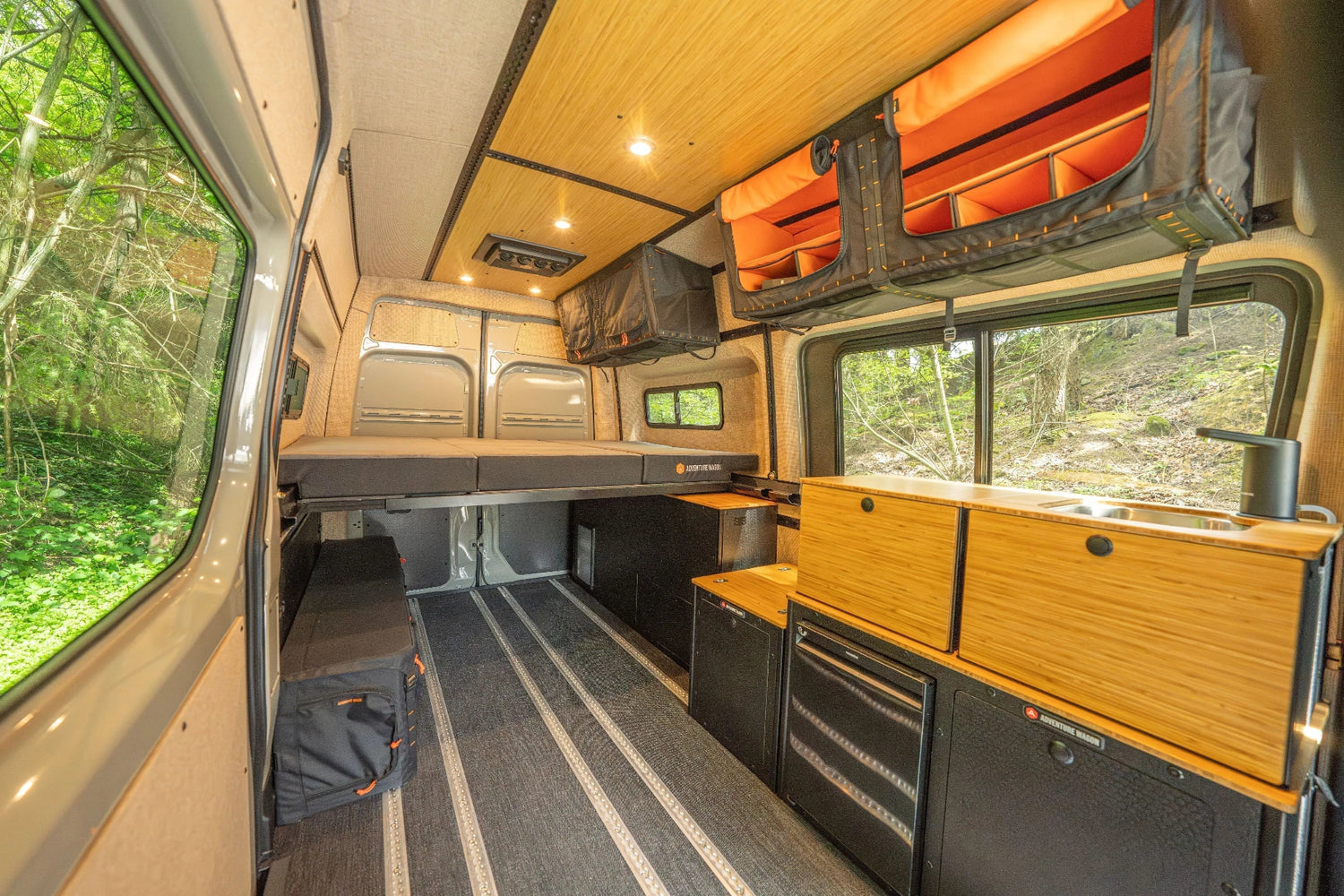 Adventure Wagon Guided Build 538 camper van interior with Switchback Galley, bed platform, Mule Bags, and open L-track floor space.
