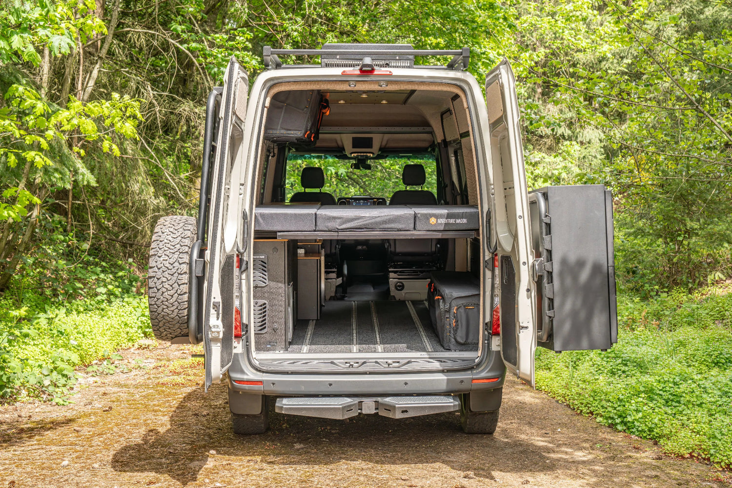 Adventure Wagon Guided Build 538 rear view with open doors, elevated bed platform, and accessible under-bed gear storage.