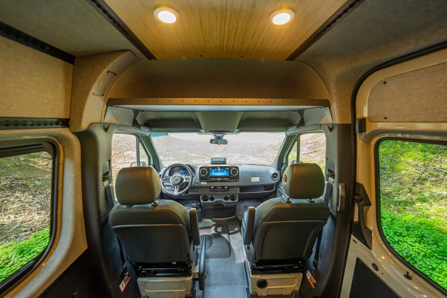 Adventure Wagon Guided Build 715 front cab interior with Mercedes Sprinter seating, dashboard, and overhead shelf.