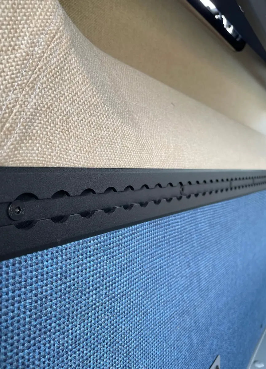 Close-up of black Adventure Wagon L-Track integrated between upholstered camper van wall panels for flexible gear and accessory mounting.