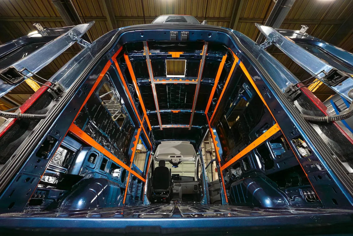 Adventure Wagon Interior System A-Frame installation inside a blue camper van showing orange structural framing before wall panels are installed.