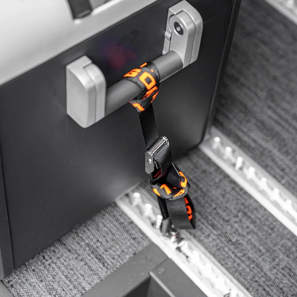 Dometic cooler secured inside a camper van with branded tie-down straps attached to the floor L-Track cargo mounting system.