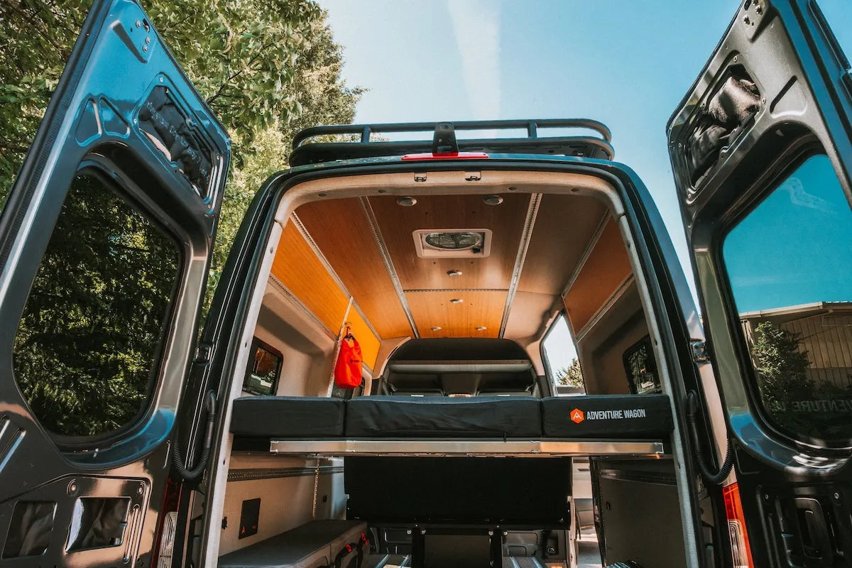Rear view inside an Adventure Wagon camper van featuring a bamboo ceiling, modular bed platform and finished upholstered interior panels.
