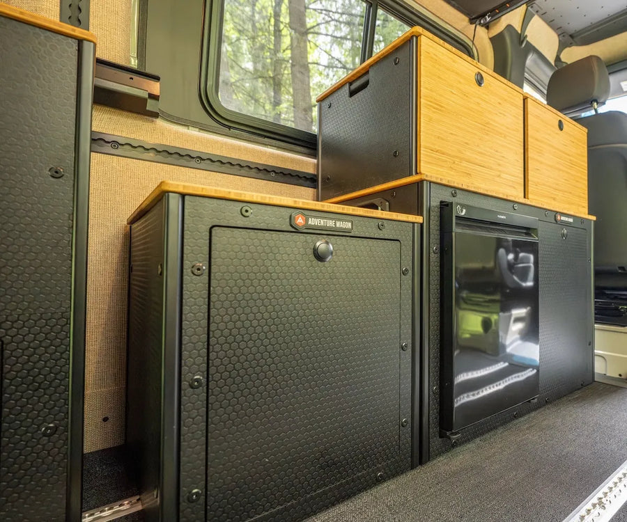 Adventure Wagon RUV interior with modular Switchback Galley, bamboo-front cabinets, integrated refrigerator, storage compartments, and open sliding door.