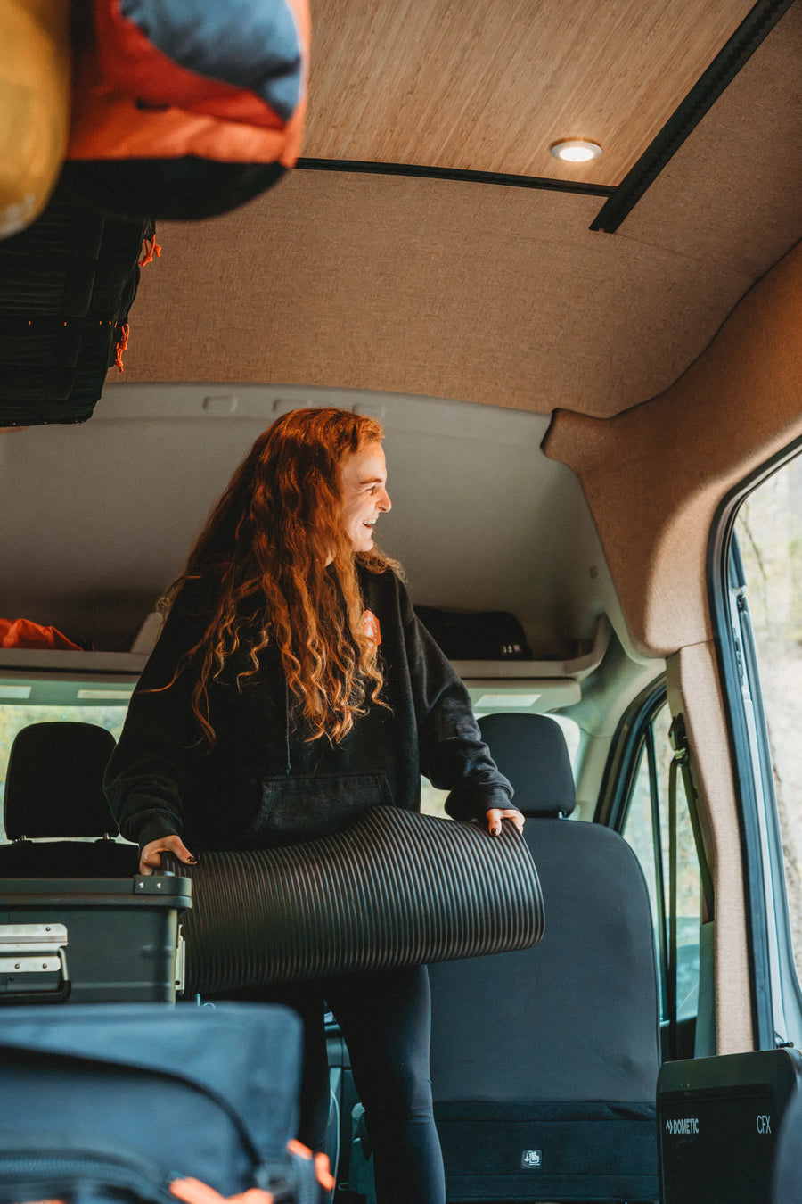 Solo traveler setting up a yoga mat in the flexible living space of the Adventure Wagon Solo Nomad van.