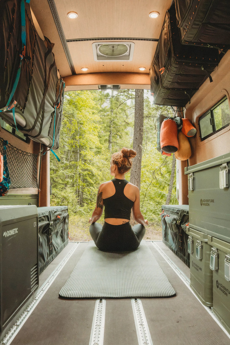 Solo traveler meditating in the open rear living space of the Adventure Wagon Solo Nomad camper van.