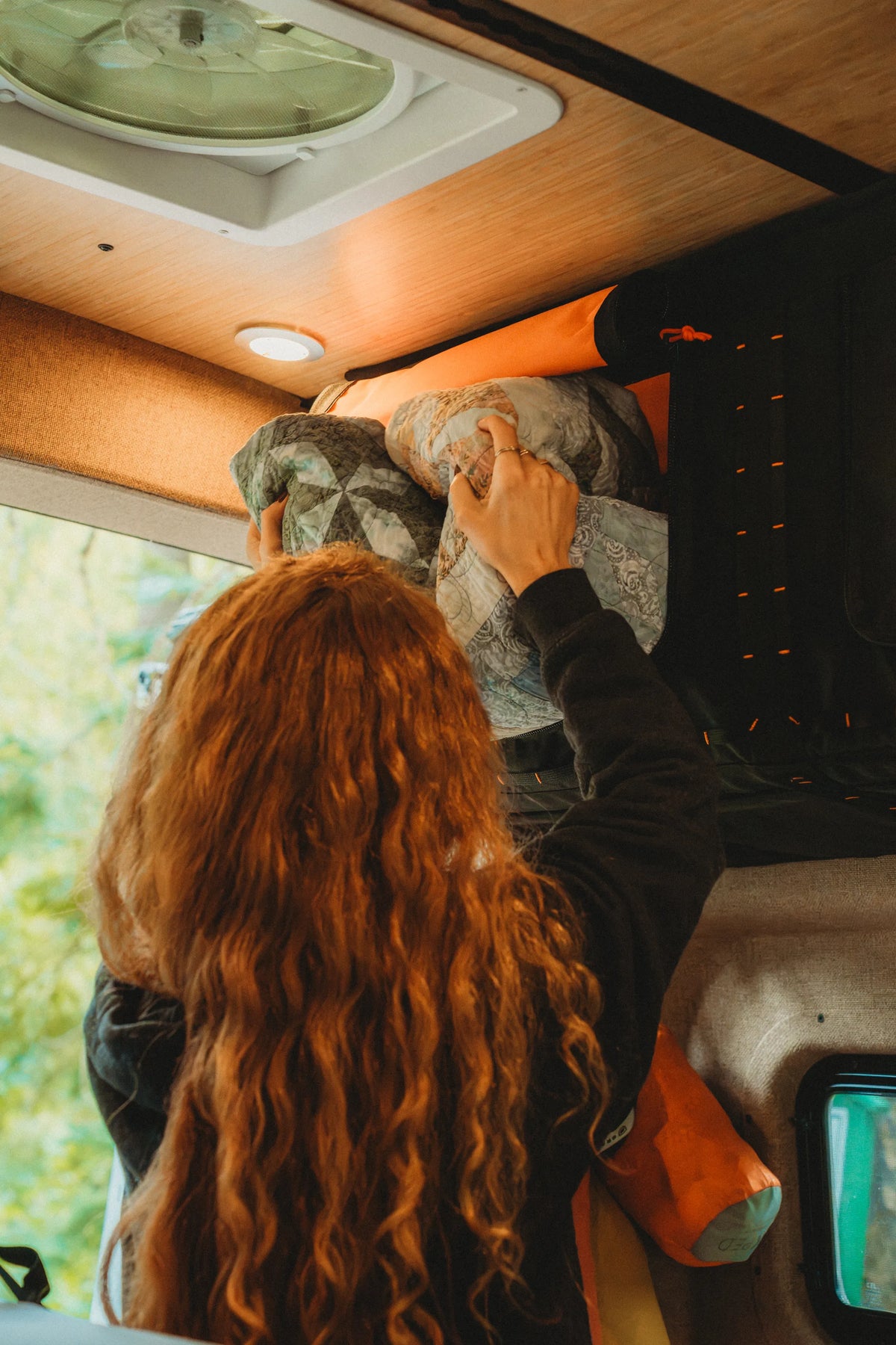 Solo traveler storing bedding in Adventure Wagon Mule Bags inside the Solo Nomad camper van.