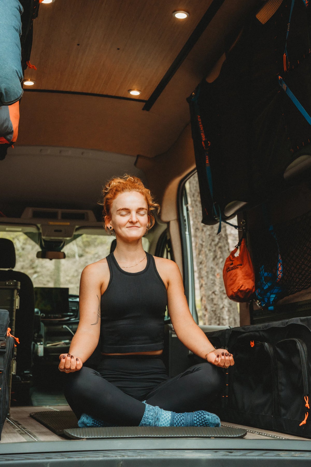 Solo traveler meditating on a yoga mat inside the Adventure Wagon Solo Nomad van.