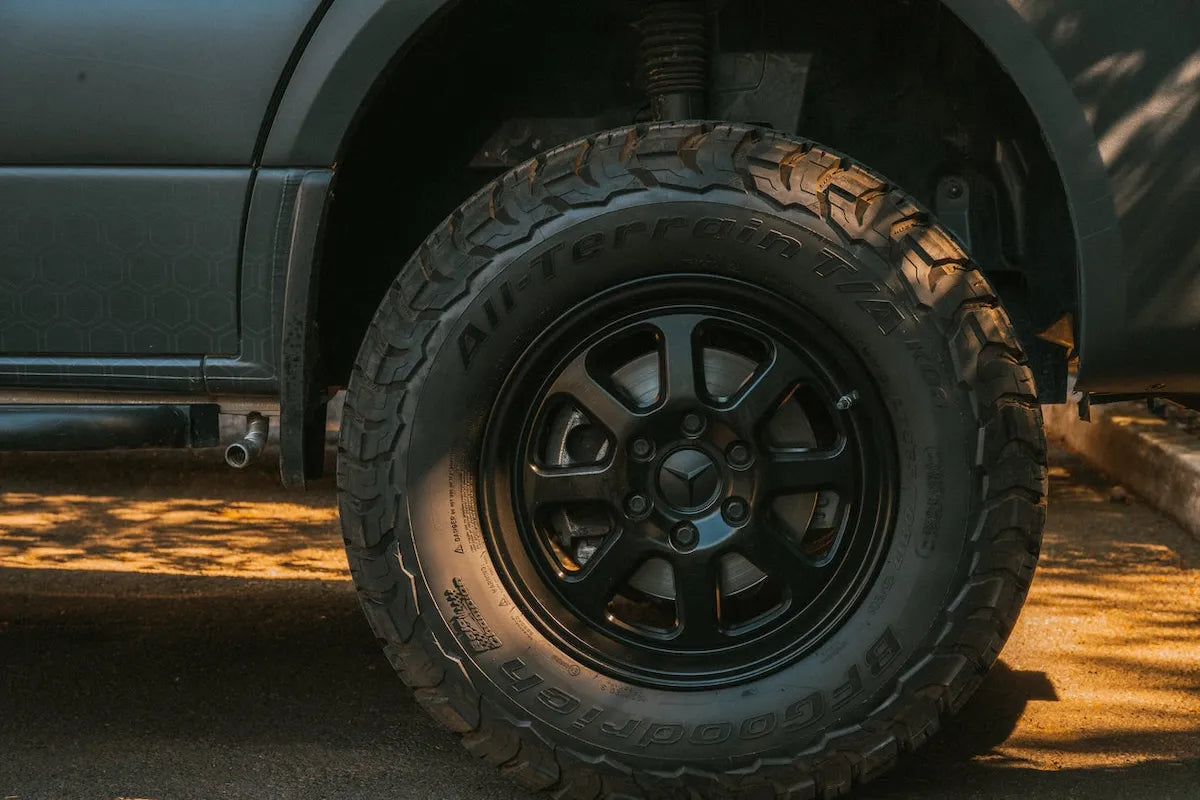 Close-up of a Mercedes-Benz Sprinter camper van wheel with black rim and BFGoodrich All-Terrain T/A tire on an Adventure Wagon build.