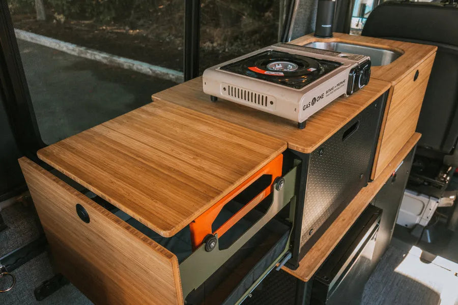 Adventure Wagon Switchback Galley with portable camp stove on bamboo countertop and modular kitchen storage.