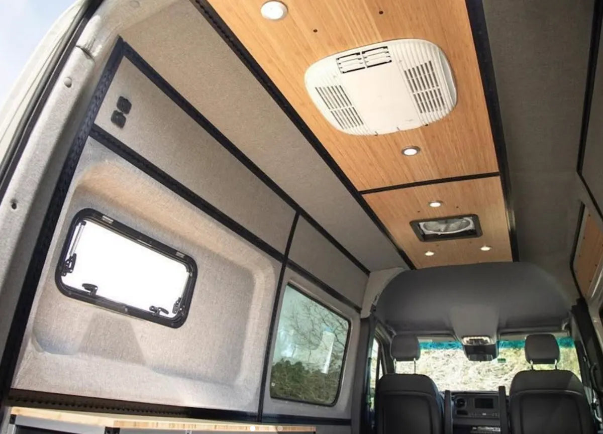 Finished Adventure Wagon camper van interior with upholstered wall and ceiling panels, bamboo accents, windows and integrated modular L-Track.