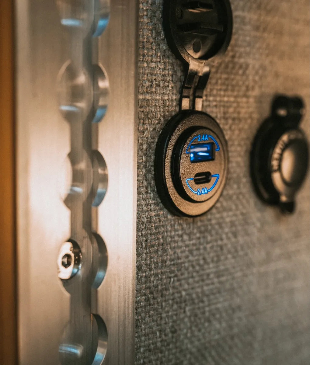 Adventure Wagon camper van electrical system detail with USB charging ports and power connections integrated into the interior wall.